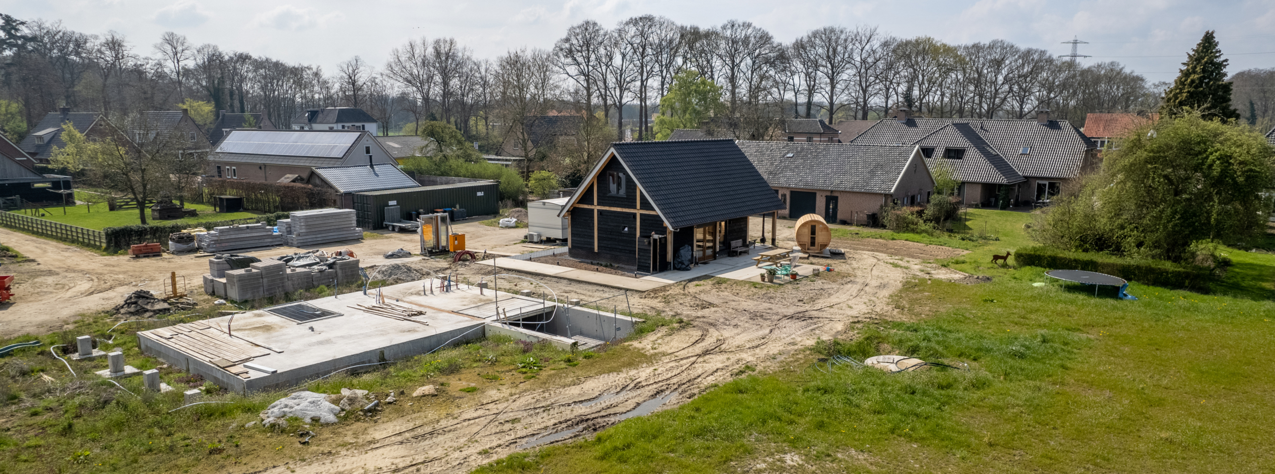Houten bijgebouw in aanbouw op bouwlocatie met fundering en materialen