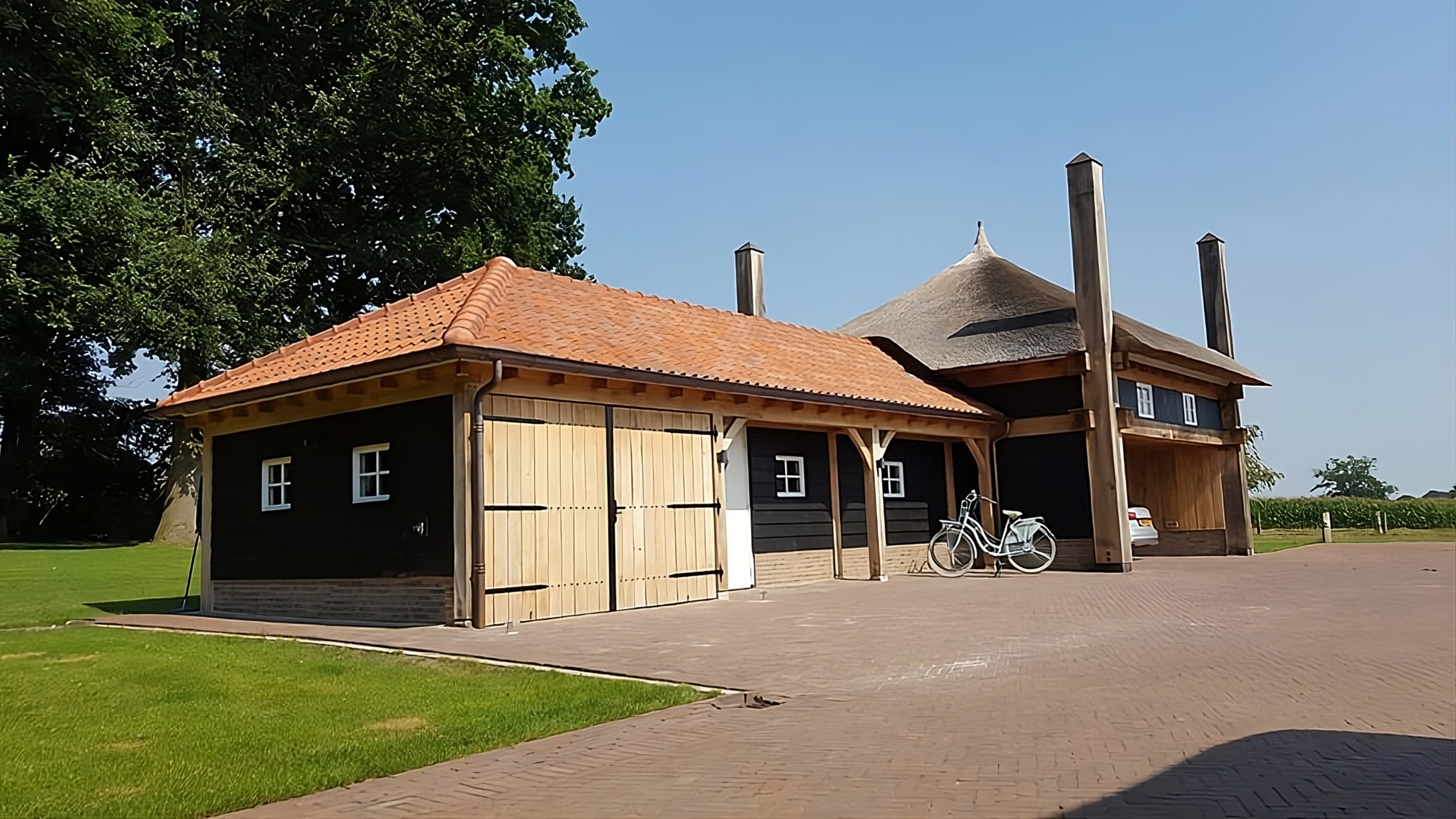 Houten bijgebouw met rood pannendak, zwarte gevel en dubbele deuren