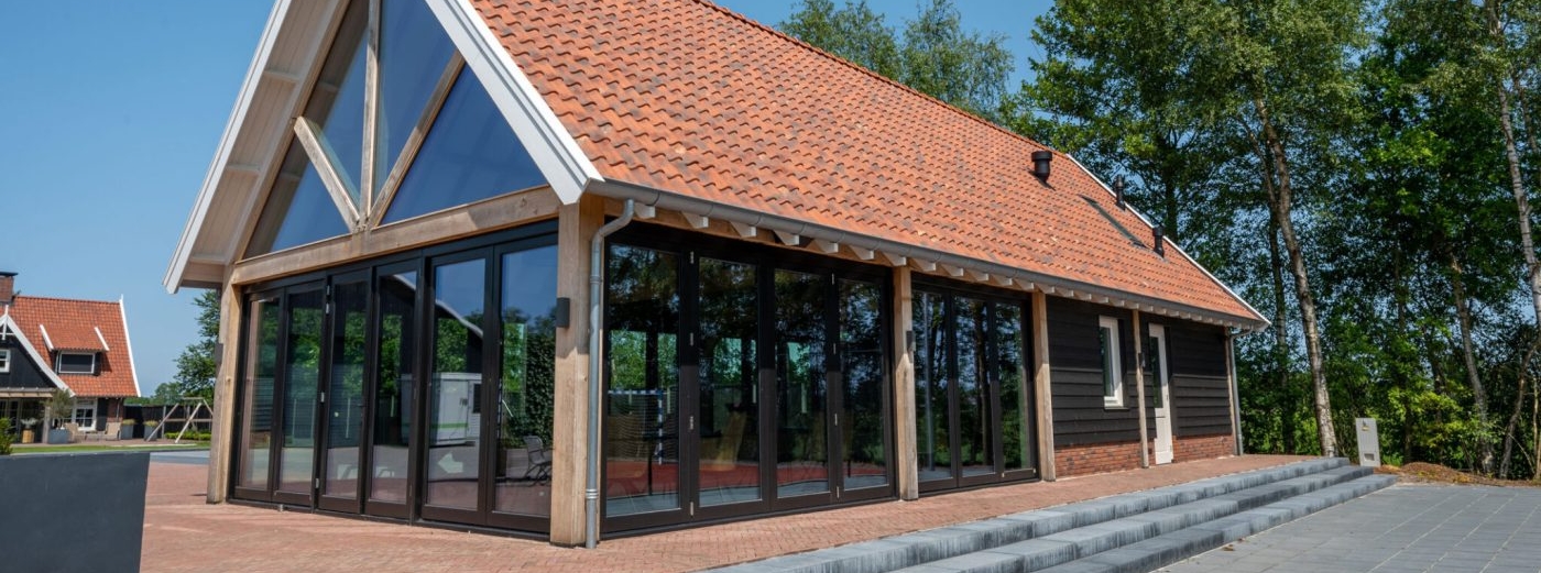 Eiken bijgebouw als bed & breakfast met zadeldak en grote glazen pui
