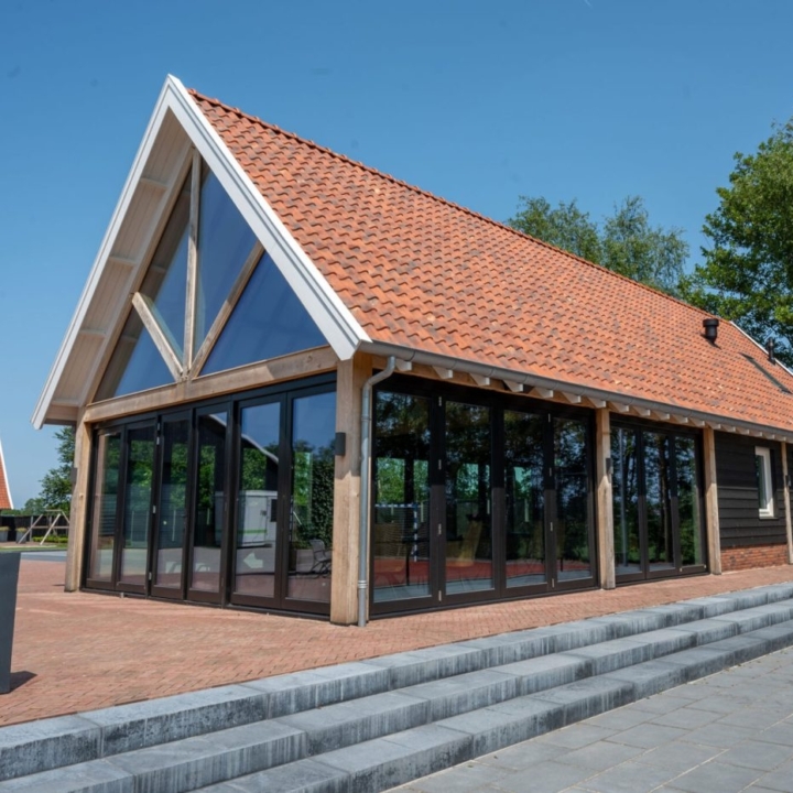 Eiken bijgebouw met glazen gevel, zadeldak en rode dakpannen
