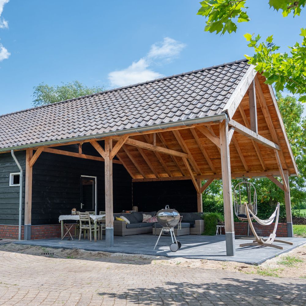 Houten bijgebouw met overdekte buitenruimte, loungehoek en zadeldak