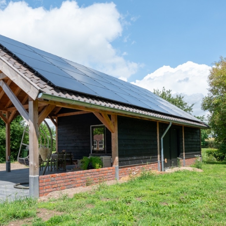 Houten carport bijgebouw met zonnepanelen en overdekte zithoek