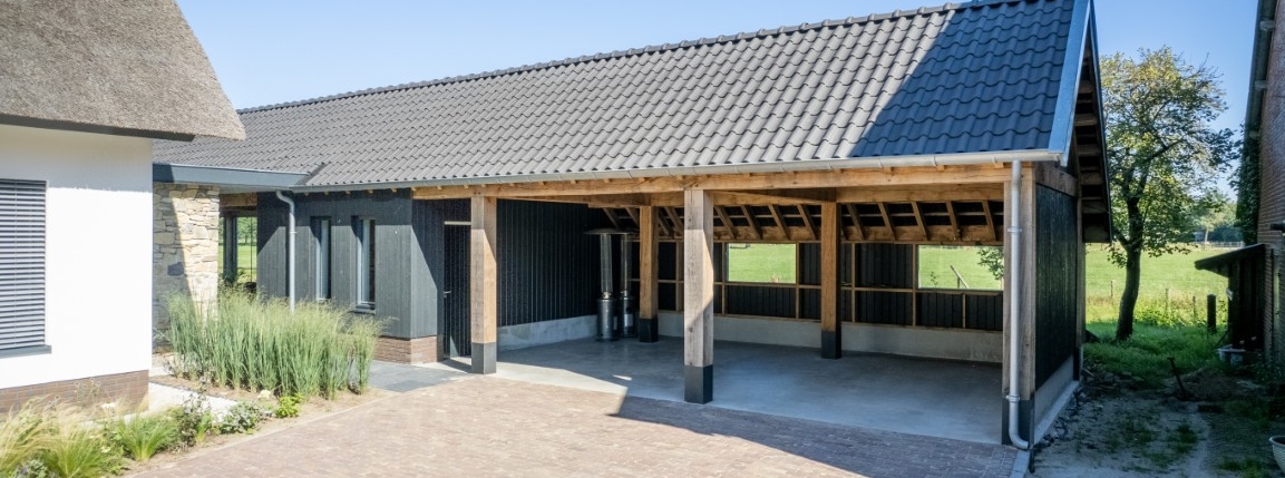Houten kapschuur met open overkapping, zwarte gevel en pannendak