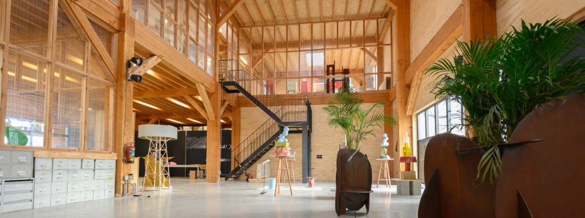 Ruim interieur van houten bijgebouw met vide, trap en houten gebinten