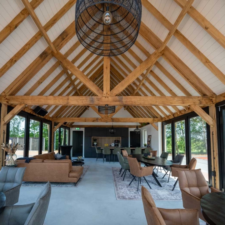 Interieur van luxe eiken bijgebouw met zichtbare houten gebinten en zithoek