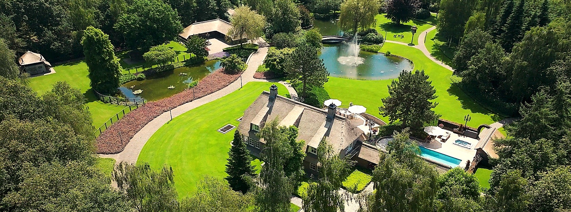 Luchtfoto van de hoofdwoning, het zwembad en de terrassen op het landgoed