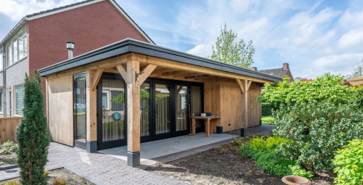 Eiken tuinhuis met plat dak, overdekte veranda en zwarte glazen puien