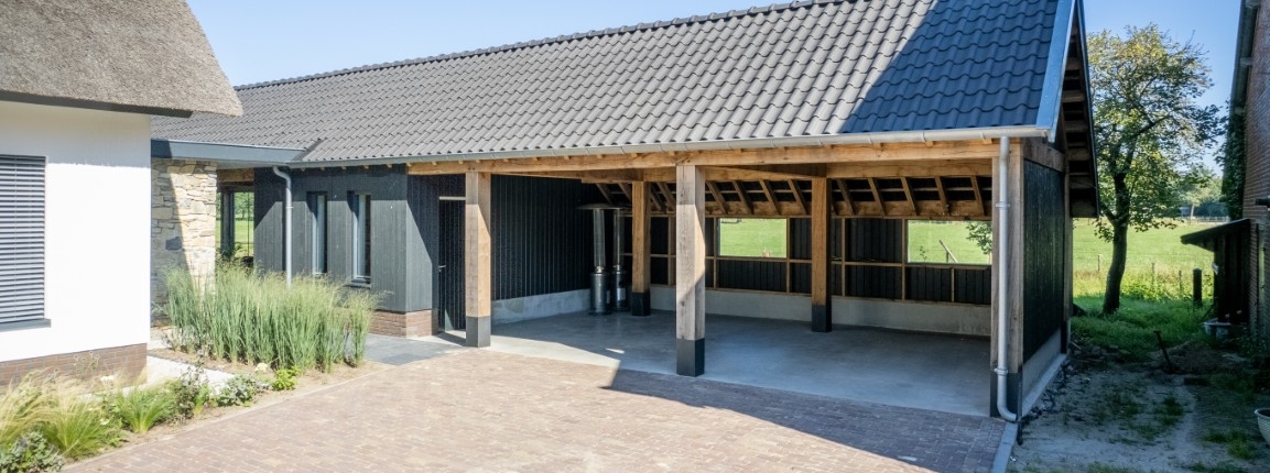 Houten kapschuur met open overkapping, zwarte gevel en pannendak